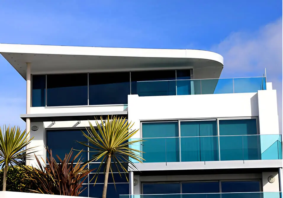 A palm tree in front of a building with glass windows.