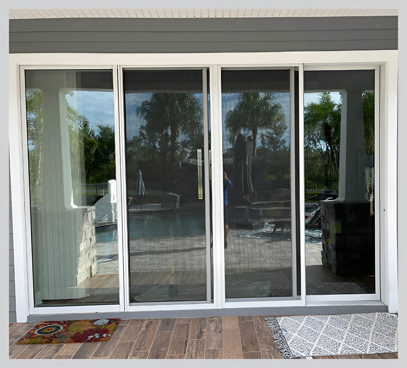 A sliding glass door with four panels and a dog on the floor.